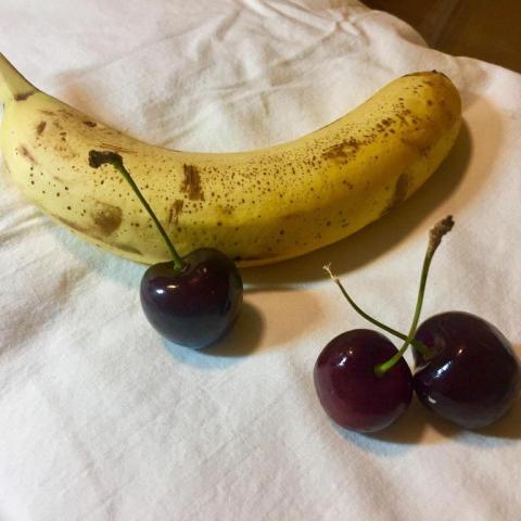 An image for watercolor painting - a banana and three cherries.