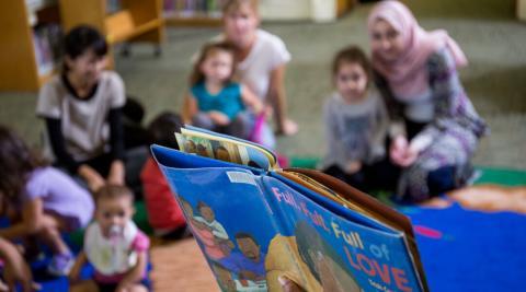 Children and parents listening to a story being read aloud
